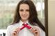 A woman in a white shirt is adjusting a red tie.