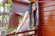 A woman in a white bodysuit leaning against a wooden fence.