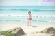 A girl standing on a beach next to the ocean.