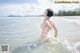 A naked woman standing in the water at the beach.