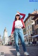 A woman in a red jacket and jeans posing for a picture.