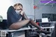 A woman sitting on top of a desk next to a printer.