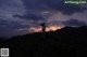 A woman standing on top of a hill at sunset.