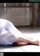 A woman in a white dress laying on the ground.