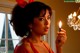 A woman in a red dress holding a lit candle.