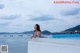 A woman in a white bathing suit sitting on the edge of a swimming pool.