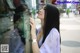 A woman looking at herself in the window of a store.