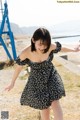 A woman in a black and white dress standing on a beach.